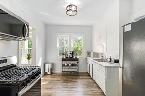 A modern kitchen with a gas stove, a refrigerator, and a window with a view of greenery. - Brand new Apartment in West Cleveland (Cleveland)