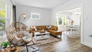 Ein modernes Wohnzimmer mit einem braunen Ledersofa, einem Korbstuhl und einem weißen Couchtisch.