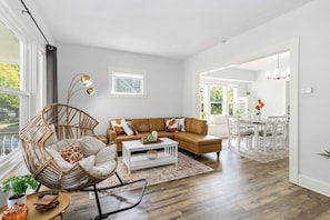 A modern living room with a brown leather sofa, a wicker chair, and a white coffee table. - Brand new Apartment in West Cleveland (Cleveland)