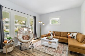 Ein Wohnzimmer mit Sofa, Sessel, Couchtisch und Stehlampe.