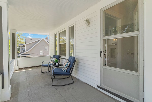 A covered porch with two rocking chairs and a large sliding glass door. - Your Coastal Getaway in West Cleveland! (Cleveland)