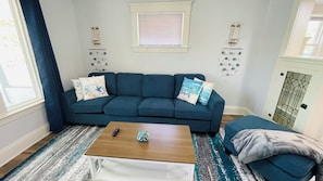 A living room with a blue sofa, a wooden coffee table, and a patterned rug. - Your Coastal Getaway in West Cleveland! (Cleveland)