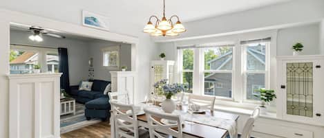 A dining area with a wooden table, white chairs, and a chandelier.