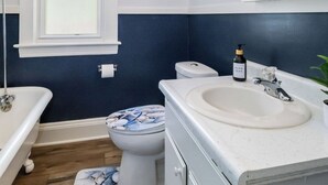 Ein Badezimmer mit einem weißen Waschbecken, einer Toilette, einem Spiegel und einem Fenster.