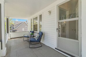 A covered porch with two rocking chairs and a large sliding glass door. - Your Beachy Getaway in West Cleveland! (Cleveland)