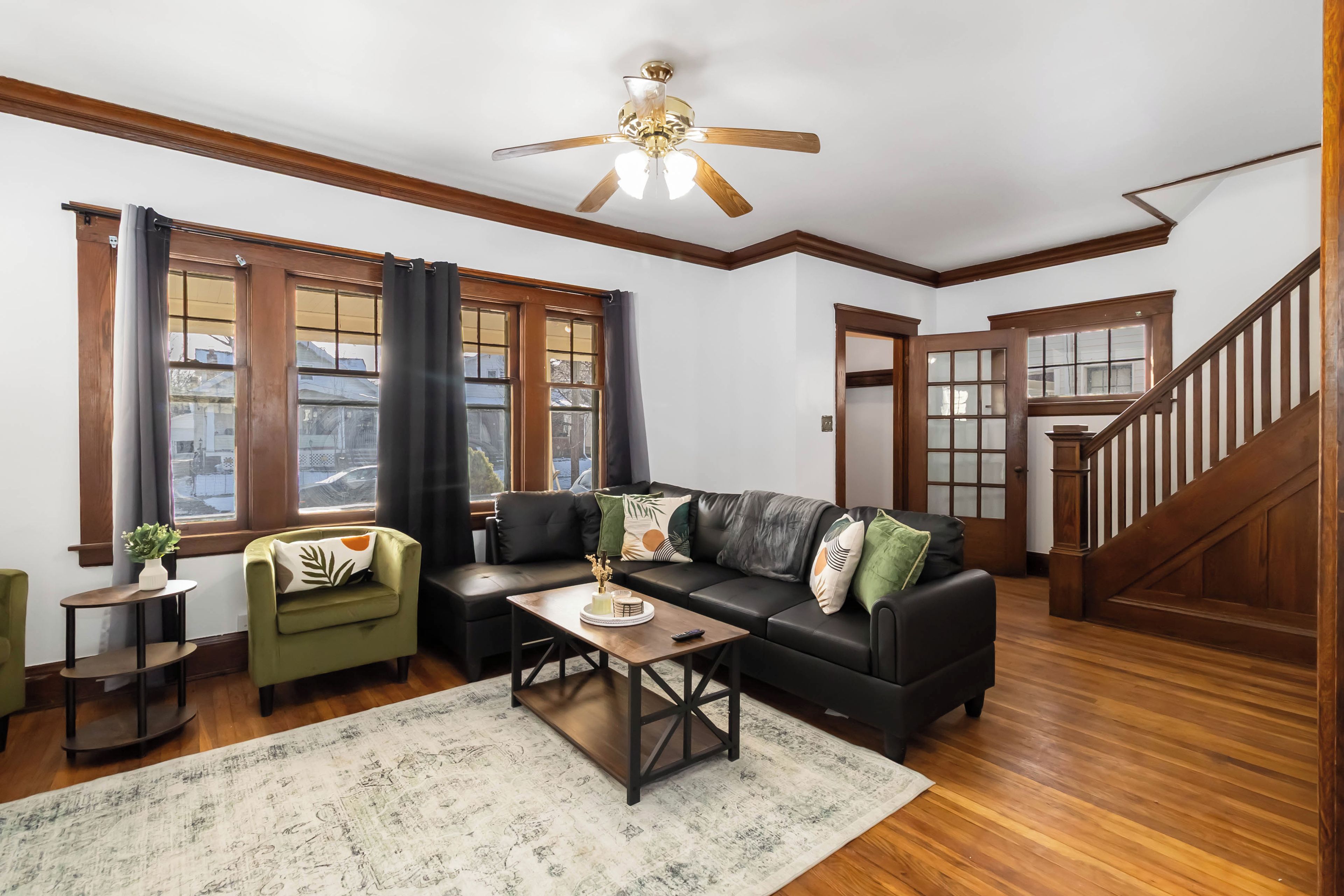 A living room with a black leather sofa, a wooden coffee table, and a ceiling fan.