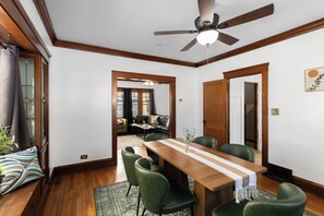 A dining area with a wooden table, green chairs, and a ceiling fan. - Single Family house Close to Freeway for easy access to everywhere in Cleveland! (Cleveland)