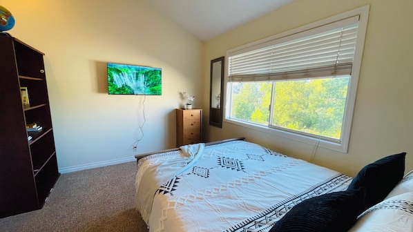 A bedroom with a bed, a dresser, a television, and a window with blinds. - Welcome to your perfect Pacific Northwest retreat! 🌲 Located on a peaceful Beaverton cul-de-sac, this 2-story home is close to Nike HQ & Intel. Enjoy fast WiFi, 3 Smart TVs, and a basketball hoop! The perfect blend of tranquility and convenience! ✨ (Beaverton)