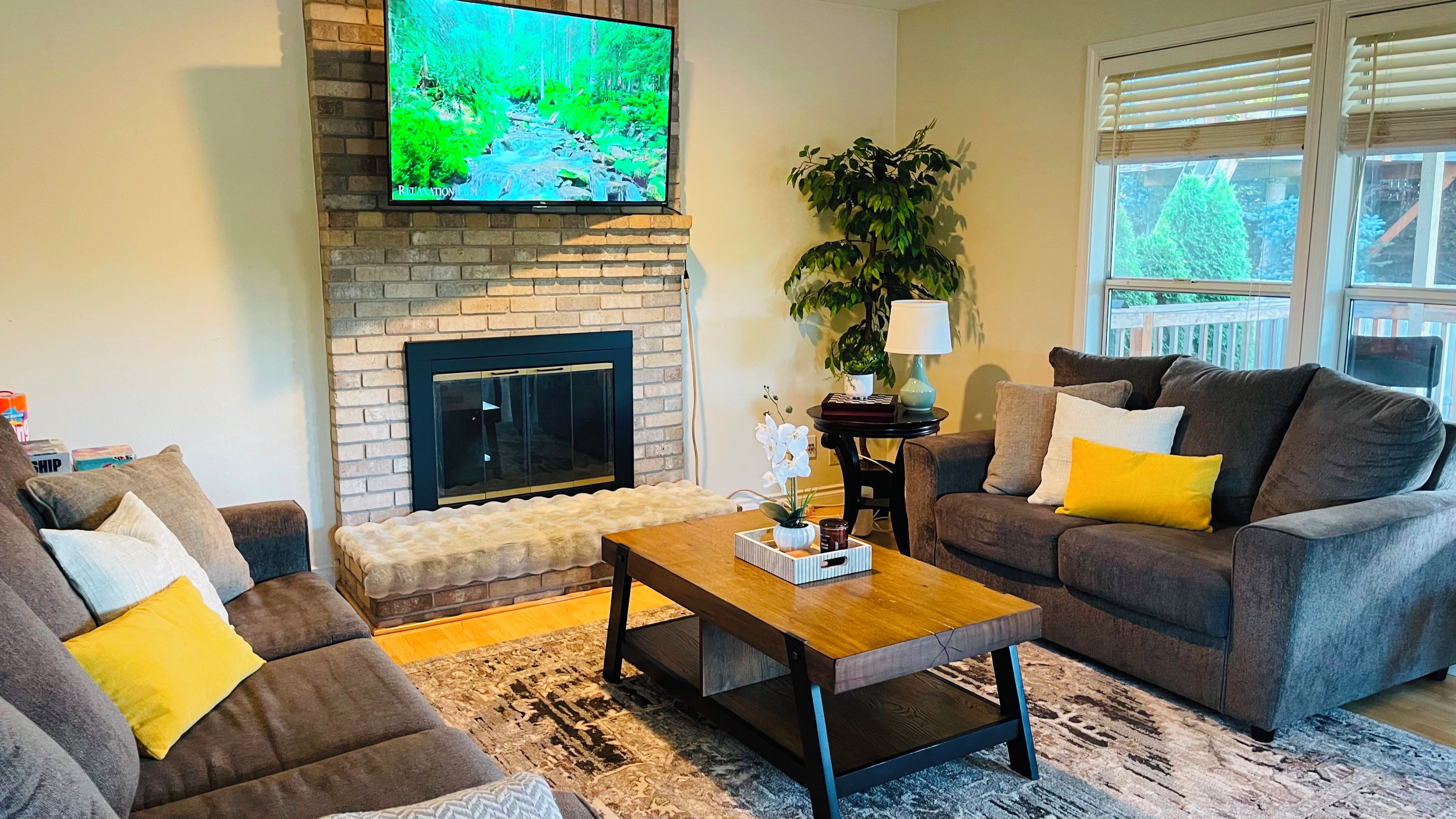 A living room with a fireplace, two sofas, a coffee table, and a TV mounted on the wall.