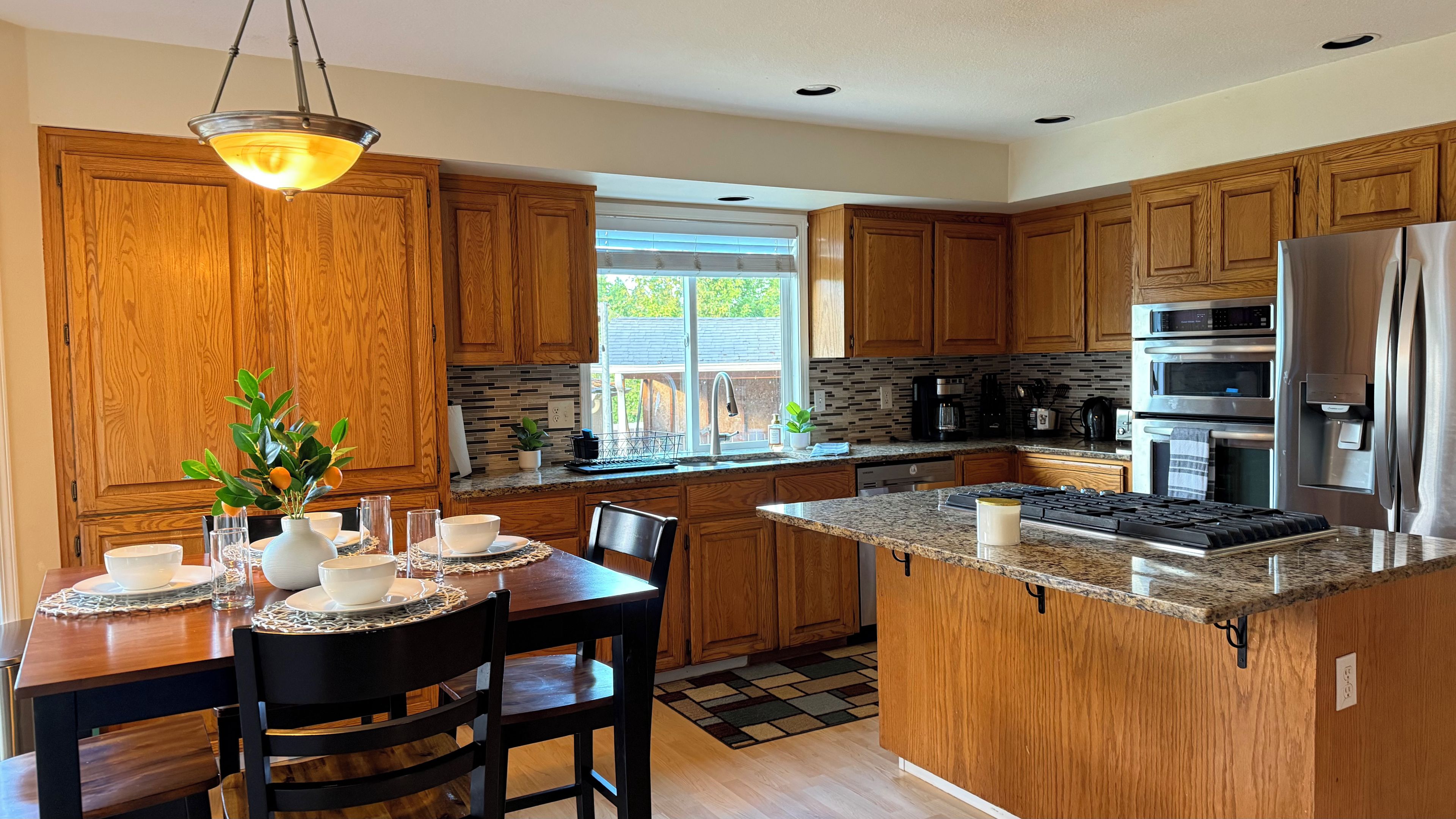 A modern kitchen with wooden cabinets, granite countertops, and stainless steel appliances.
