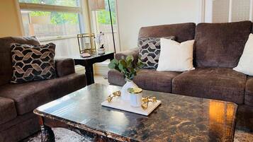 A living room with two brown sofas, a glass coffee table, and decorative items.