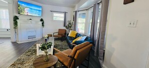 A modern living room with a fireplace, a TV mounted on the wall, and a sofa with cushions. - Recent  Remodeled UP Unit 3bedroom in West CLE (Cleveland)