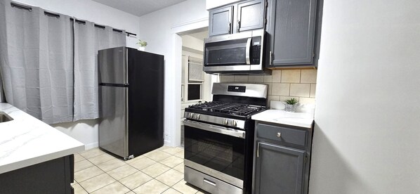 Eine kompakte Küche mit Kühlschrank, Mikrowelle, Herd, Backofen und Schränken.