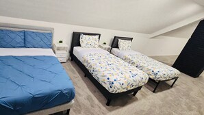Ein Schlafzimmer mit einem großen Bett und zwei kleineren Betten, jedes mit unterschiedlicher Bettwäsche.