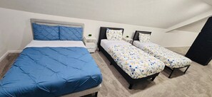 A bedroom with a large bed and two smaller beds, each with distinct bedding patterns. - Recent  Remodeled UP Unit 3bedroom in West CLE (Cleveland)