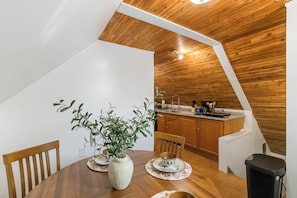 A dining area with a wooden table, chairs, and a vase with green plants. - Lakewood Cabin-style third floor Getaway 2p2 (Lakewood)