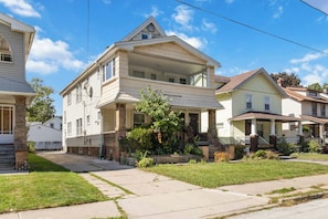 A two-story residential building with a front porch and a small garden area. - Lakewood Cabin-style third floor Getaway 2p2 (Lakewood)