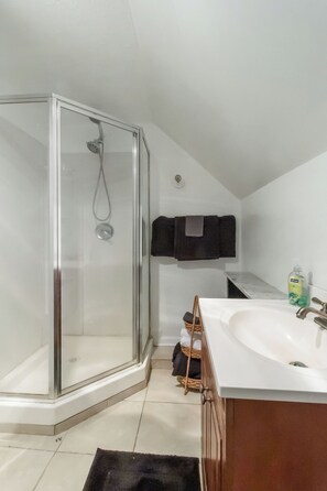 A modern bathroom with a glass shower enclosure, a white sink, and a towel rack. - Lakewood Cabin-style third floor Getaway 2p2 (Lakewood)
