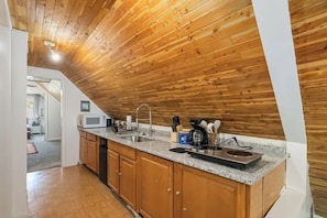 Una cocina con techo de madera, encimera de granito y electrodomésticos modernos.