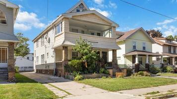 A two-story residential building with a front porch and a small garden area.
