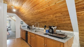 A kitchen with wooden ceiling, granite countertop, and modern appliances.
