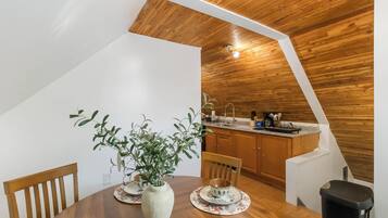 A dining area with a wooden table, chairs, and a vase with green plants.