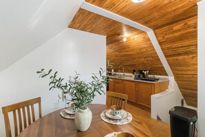 Een eethoek met een houten tafel, stoelen en een vaas met groene planten.