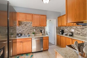 A modern kitchen with wooden cabinets, a stainless steel dishwasher, and a tiled backsplash. - Extremely walkable Lakewood & Rocky River w/Patio. (Lakewood)
