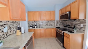 Una cocina con armarios de madera, una estufa de acero inoxidable y un salpicadero de azulejos.