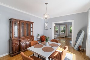 A dining area with a wooden cabinet, a chandelier, and a dining table with placemats.