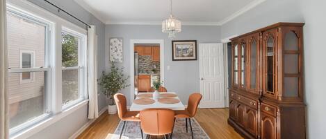 Un espace repas comprenant une table, des chaises, un lustre et un buffet en bois.