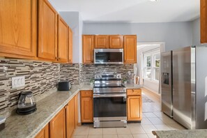 A modern kitchen with wooden cabinets, a stainless steel refrigerator, and a built-in oven.
