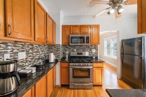 A kitchen with wooden cabinets, a microwave, stove, and a refrigerator. - Walkable Lakewood & Rocky River up Level (Lakewood)
