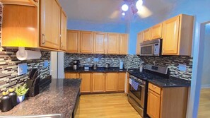 A kitchen with wooden cabinets, a microwave, a stove, and a tiled backsplash. - Walkable Lakewood & Rocky River up Level (Lakewood)