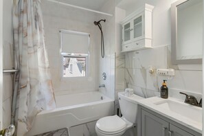 A modern bathroom with a bathtub, toilet, and a window. - Walkable to Lakewood & Rocky River  2nd floor (Lakewood)