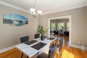 Een eetgedeelte met een marmeren tafel, zwarte stoelen en een kroonluchter.