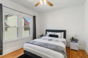 A bedroom with a bed, two bedside tables, a ceiling fan, and a window with curtains. - Walkable to Lakewood & Rocky River  2nd floor (Lakewood)
