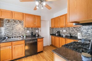 A kitchen with wooden cabinets, a black countertop, a stainless steel dishwasher, and a tiled backsplash. - Walkable to Lakewood & Rocky River  2nd floor (Lakewood)