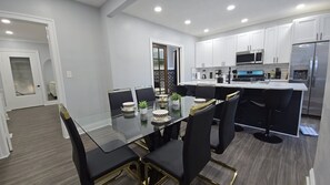 A modern kitchen with white cabinets, a stainless steel refrigerator, and a glass dining table with black chairs. - West BLVD Single Family house Close to Freeway for easy access to everywhere in Cleveland! (Cleveland)