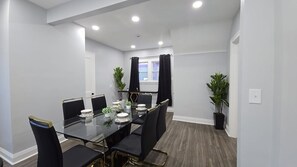 Une salle de conférence avec une table en verre, des chaises noires et des plantes en pot.