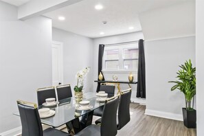 A modern dining area with a glass table, black chairs, and a potted plant. - West BLVD Single Family house Close to Freeway for easy access to everywhere in Cleveland! (Cleveland)