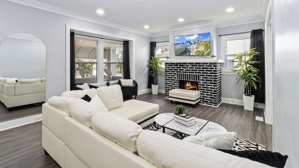 Una sala de estar moderna con un sofá blanco, una chimenea y un televisor montado en la pared.