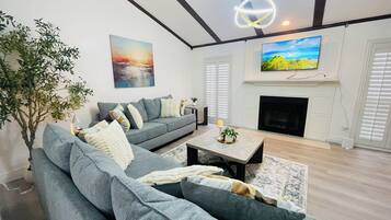 A living room with a grey sofa, a fireplace, a television, and a painting on the wall.