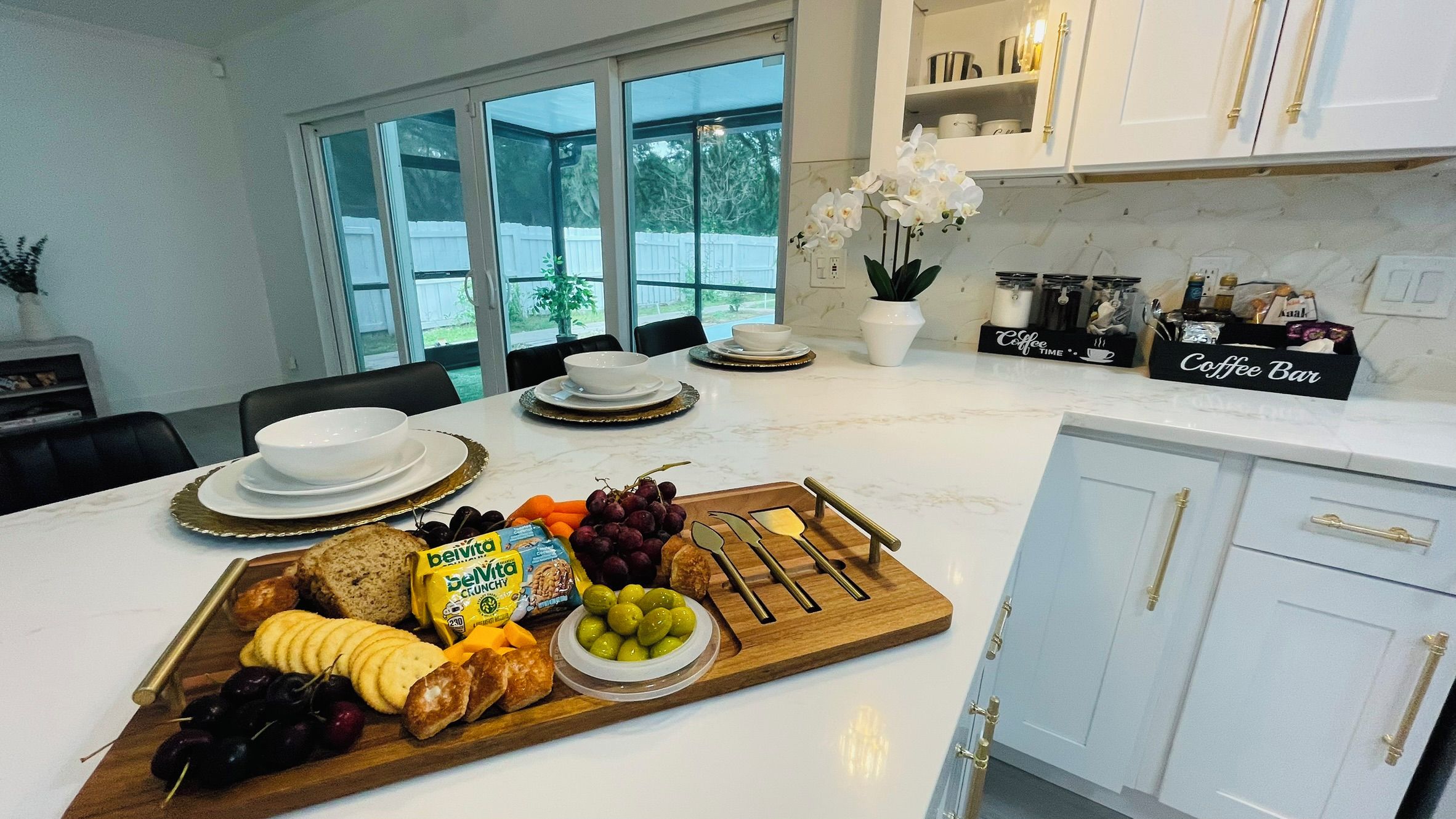 A kitchen with a marble countertop, a coffee bar, and a dining area with a table set for two.
