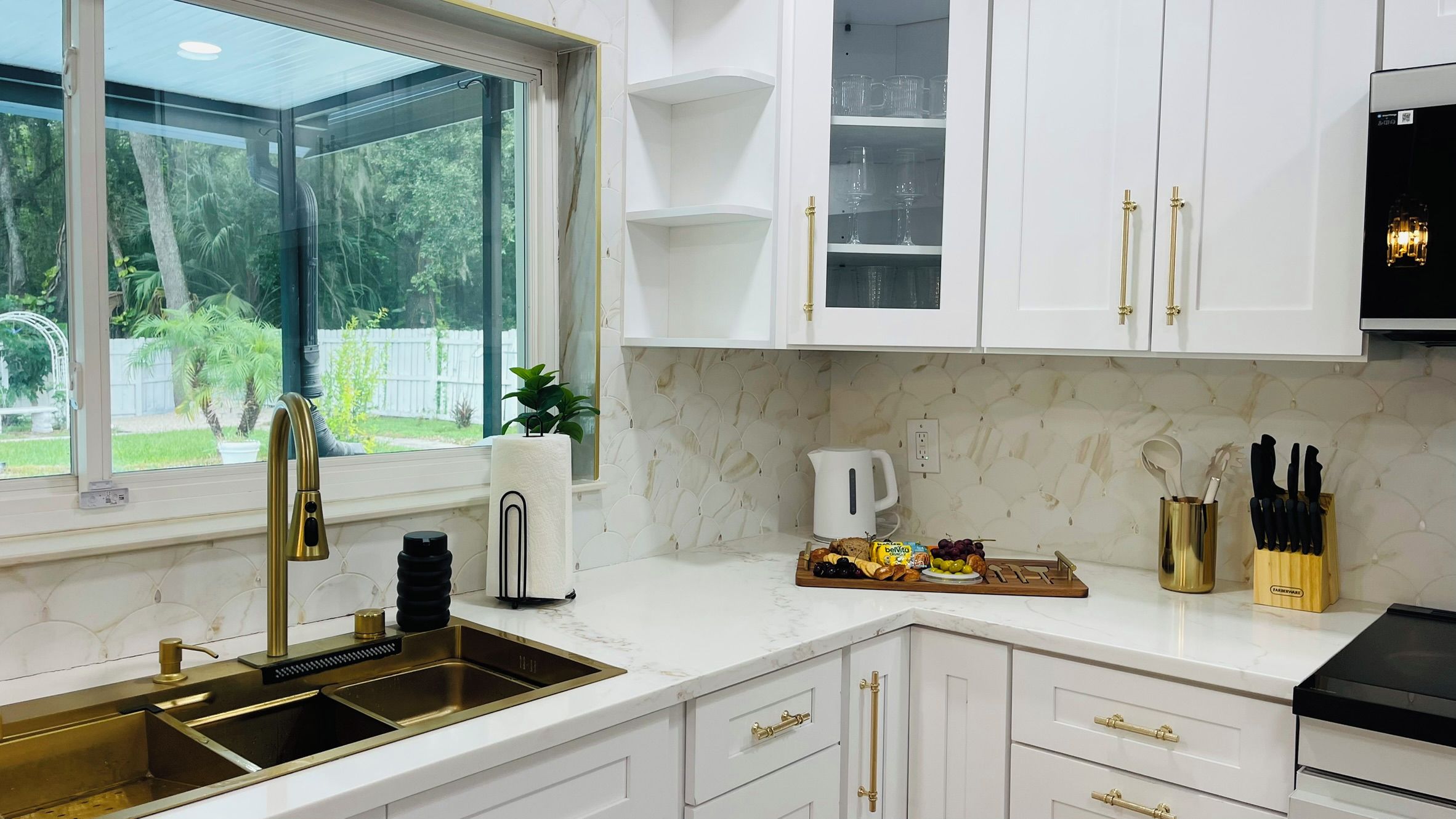 A modern kitchen with white cabinetry, a stainless steel sink, and a breakfast bar.