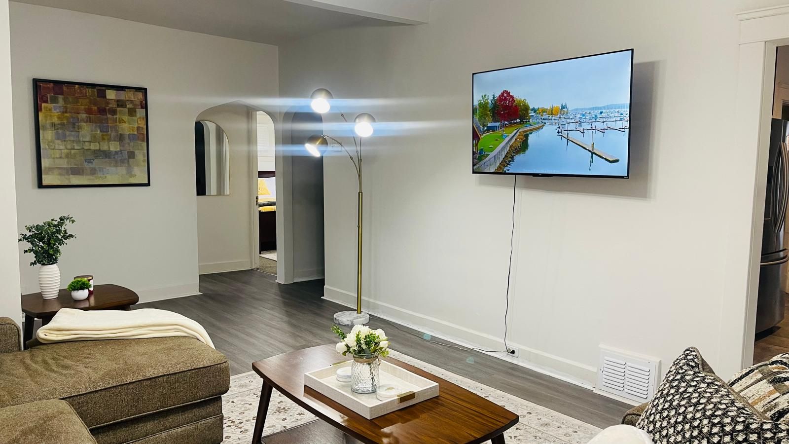 Un saló modern amb un televisor de pantalla plana muntat a la paret, una taula de centre amb un ram de flors i un sofà.