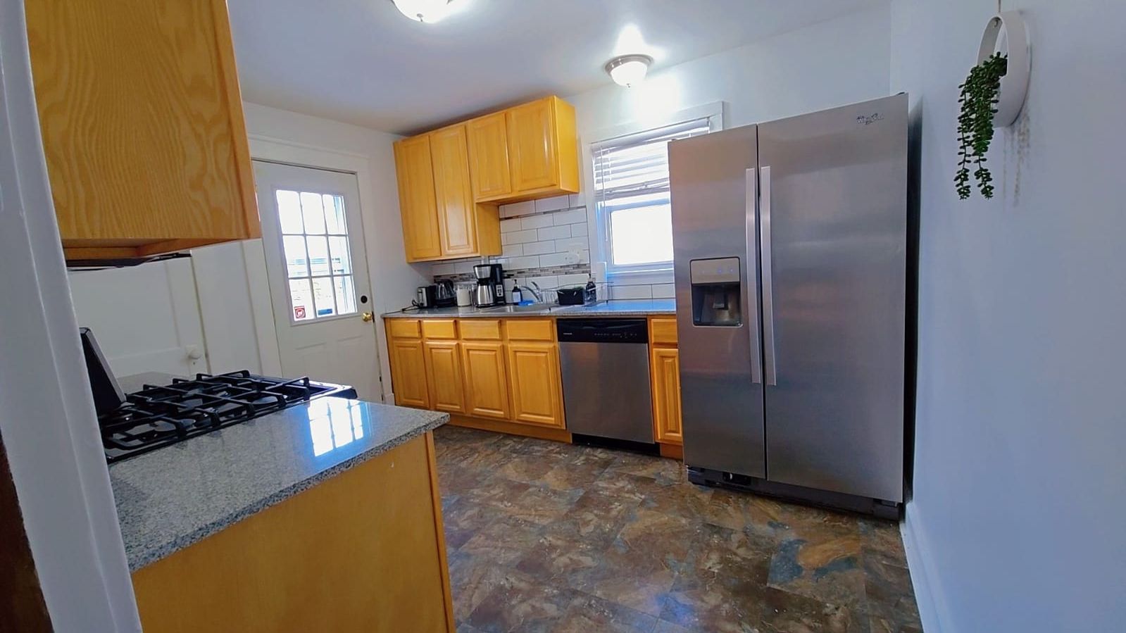 A kitchen with wooden cabinets, a stainless steel refrigerator, a gas stove, and a dishwasher.