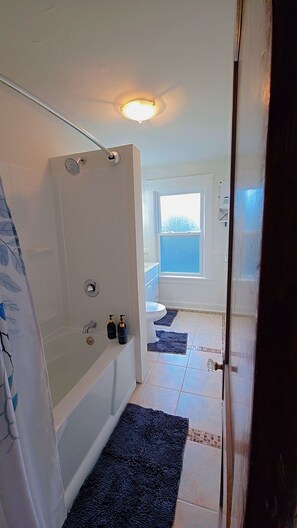 A bathroom with a shower, toilet, and a window. - Central West Blvd 2bedroom Apartment close to HWY (Cleveland)