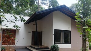 Ein modernes Haus mit flachem Dach, einer Veranda und einem großen Fenster.