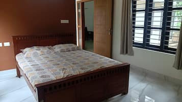Un dormitorio con cama de madera, un ventanal con persianas y una puerta que da a otra habitación.